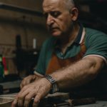 Elderly craftsman concentrating on handmade projects in a traditional workshop setting.